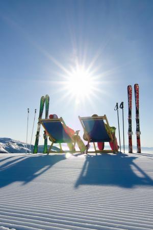 Zwei Skifahrer machen Pause und nutzen die Liegestühle die an den Pisten aufgestellt wurden. Ein Service der Region Turracher Höhe.