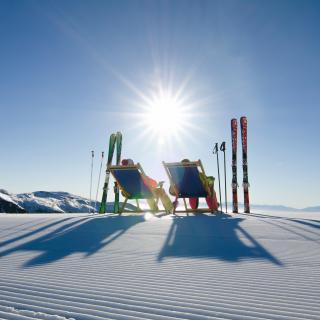 Zwei Skifahrer machen Pause und nutzen die Liegestühle die an den Pisten aufgestellt wurden. Ein Service der Region Turracher Höhe.
